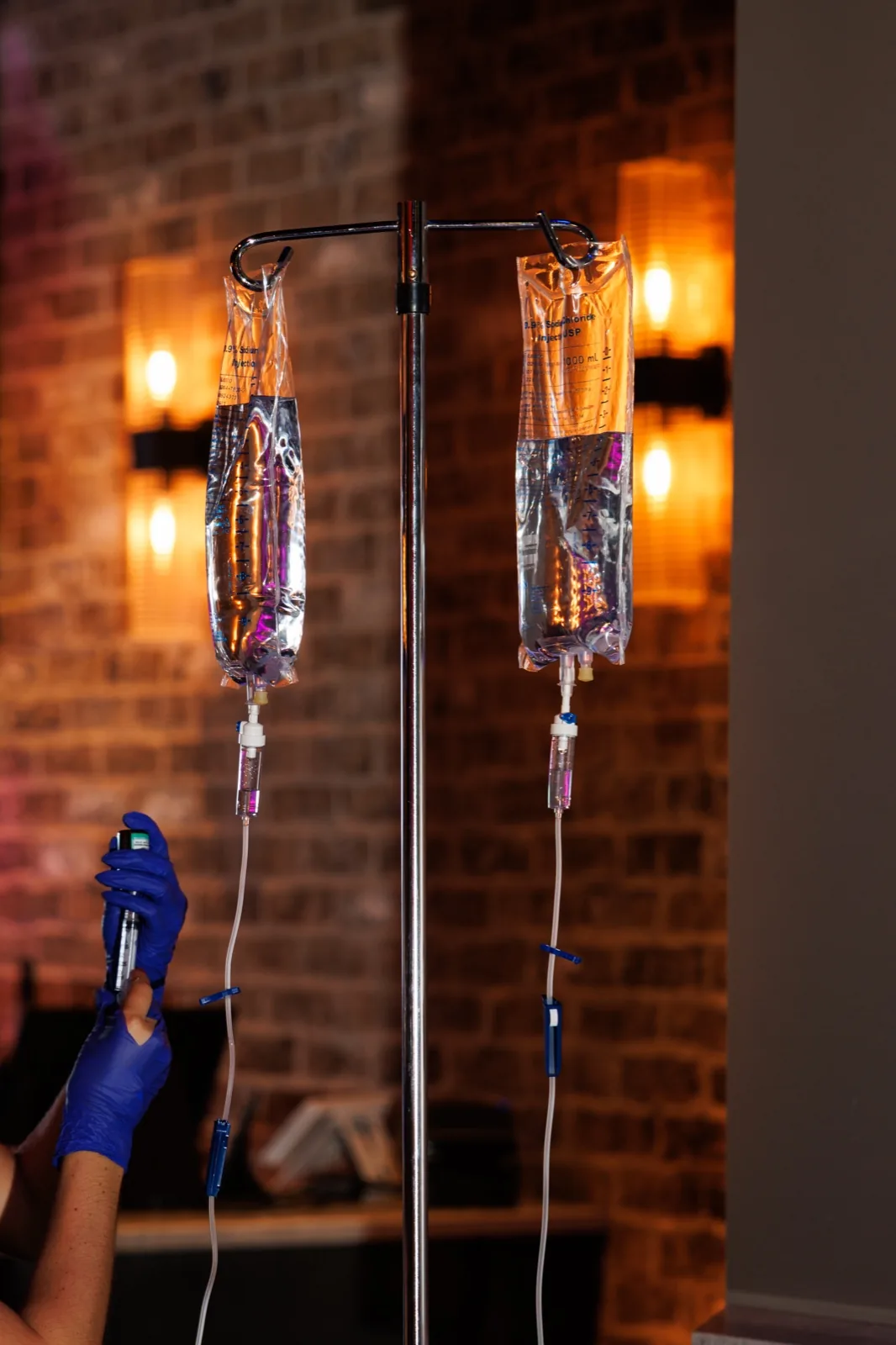 IV bags hanging in a brick-walled bar lit by Edison bulbs
